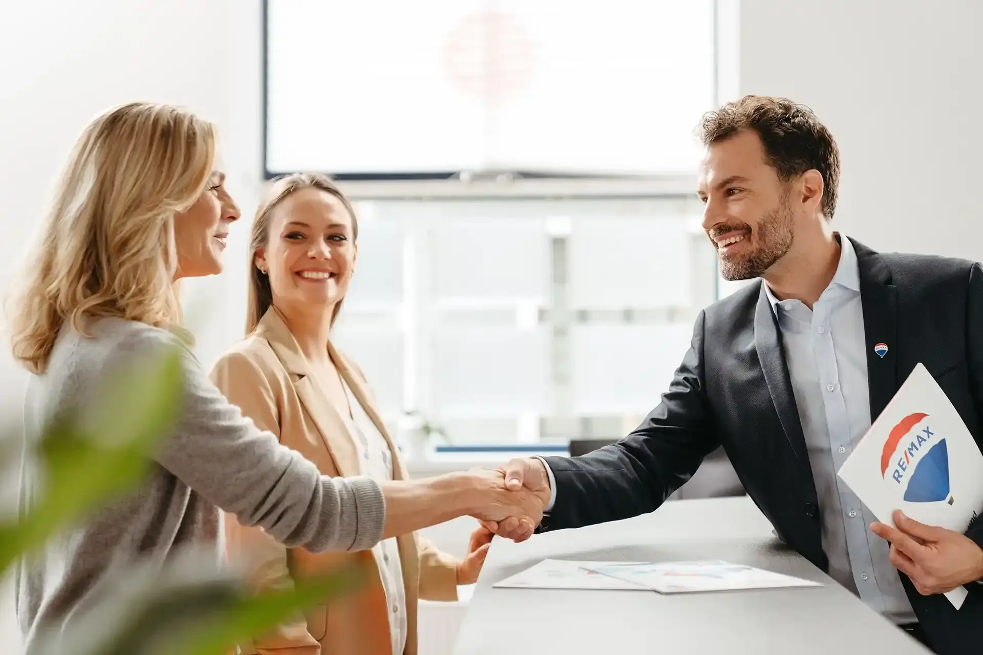Agent RE/MAX shaking hands with clients
